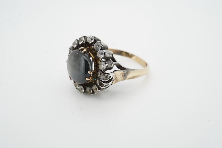 An Indian? yellow and white metal (shank stamped 18k), greyish star sapphire and simulated diamond cluster set dress ring, size O, gross weight 8.2 grams. Condition - poor (stone missing).